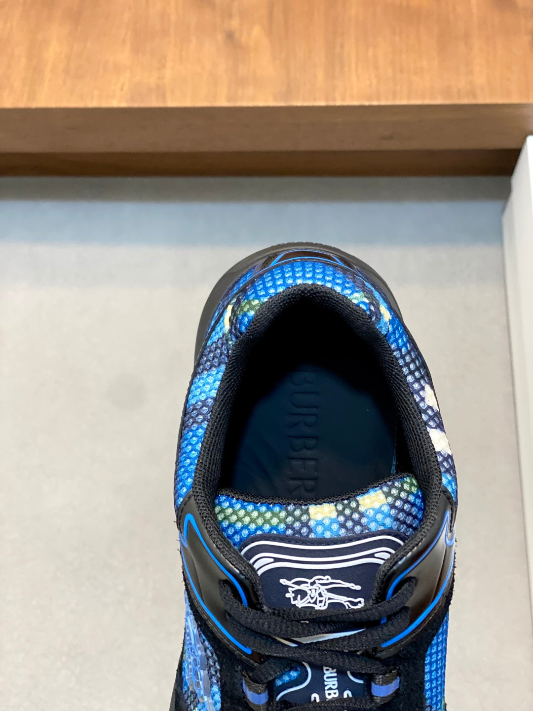 Blue patterned athletic sneaker toe view with black interior lining and laces