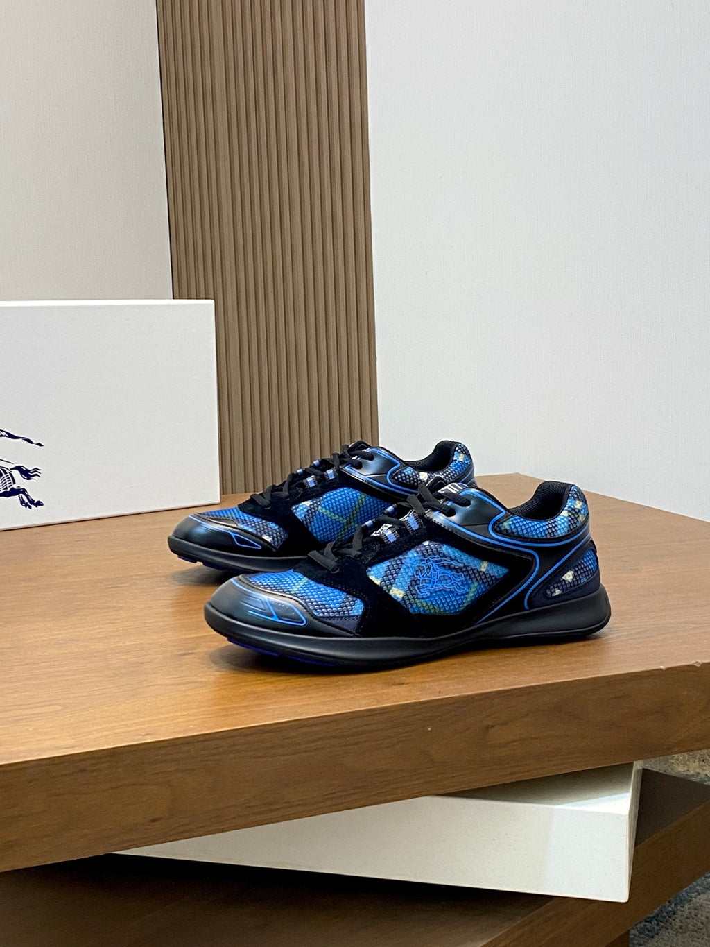 Pair of blue and black athletic sneakers on shelf with lace-up fronts