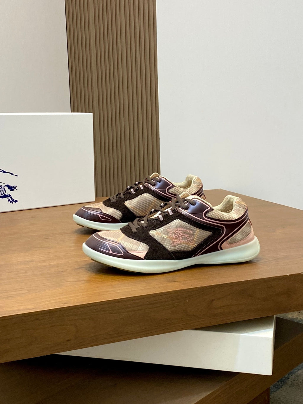 Burberry sneakers on display, maroon and black uppers with beige textured panels