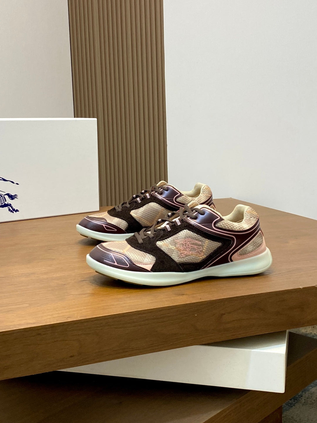 Burberry sneakers on display, maroon and black uppers with beige textured panels