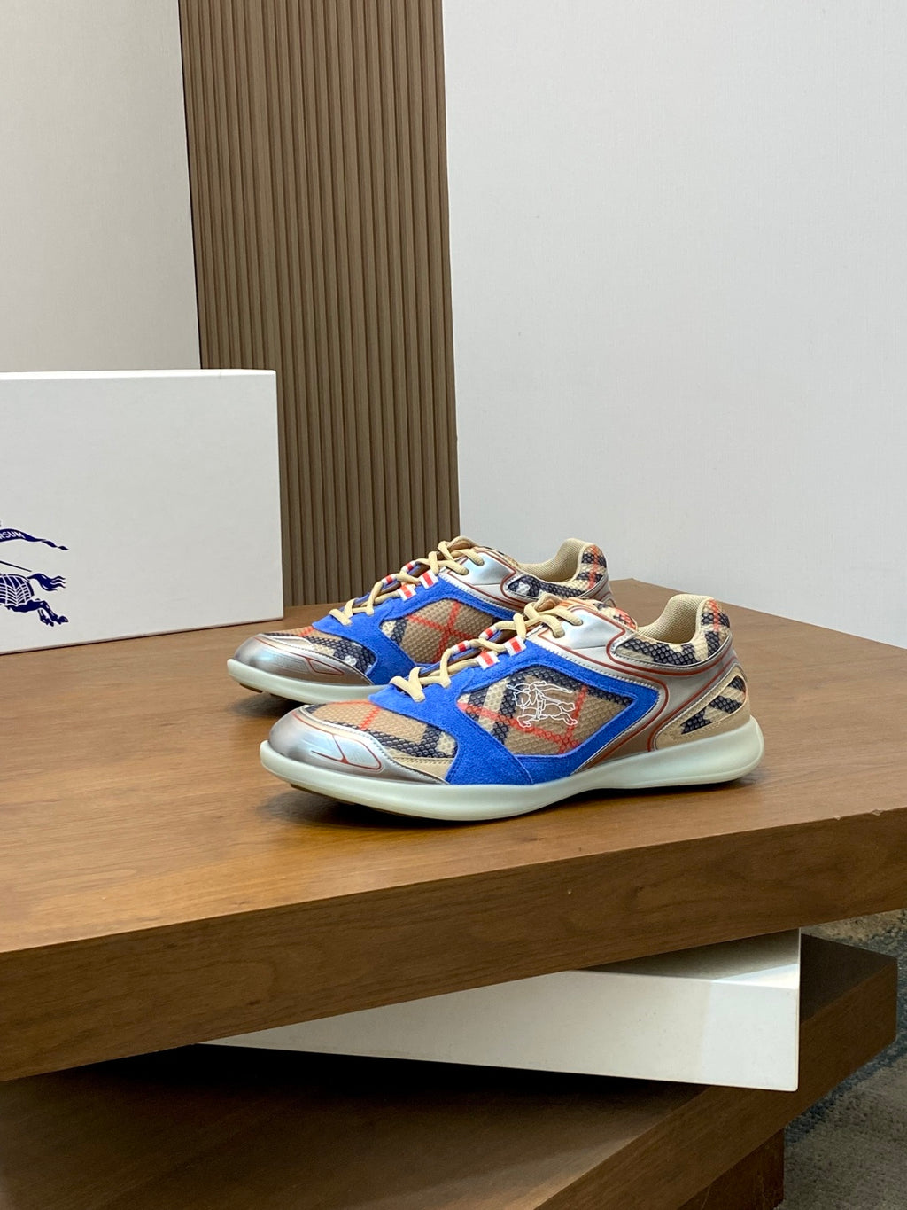 Blue multicolor Burberry sneakers, angled side view on a display platform