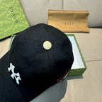 Gucci cap in black with a round gold button at the crown and logo detail