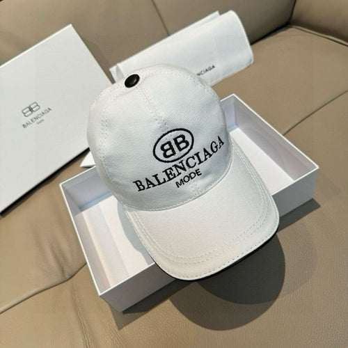 White Balenciaga baseball cap on box, black logo and small top button.