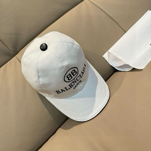 White Balenciaga baseball cap with black logo patch and round button top.