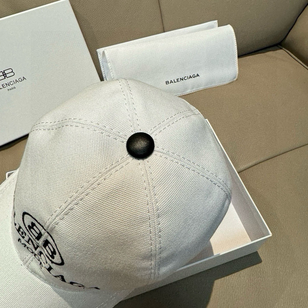 White Balenciaga baseball cap close-up of textured fabric and top button.