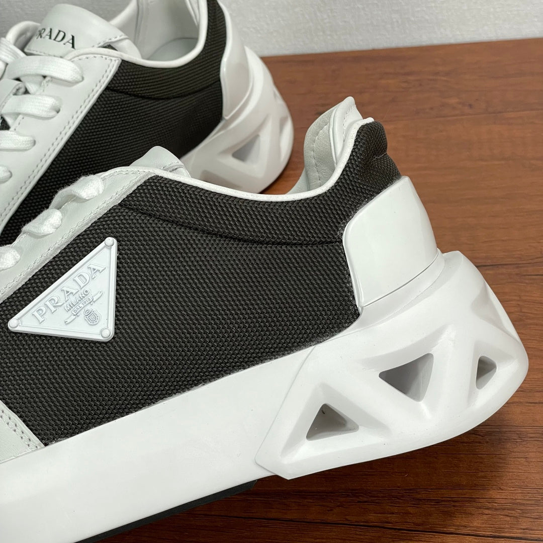 Prada unisex sneaker side close-up, black upper with white overlays and chunky sole.