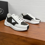 Prada unisex sneakers, black mesh and white leather lace-up, side view of pair.