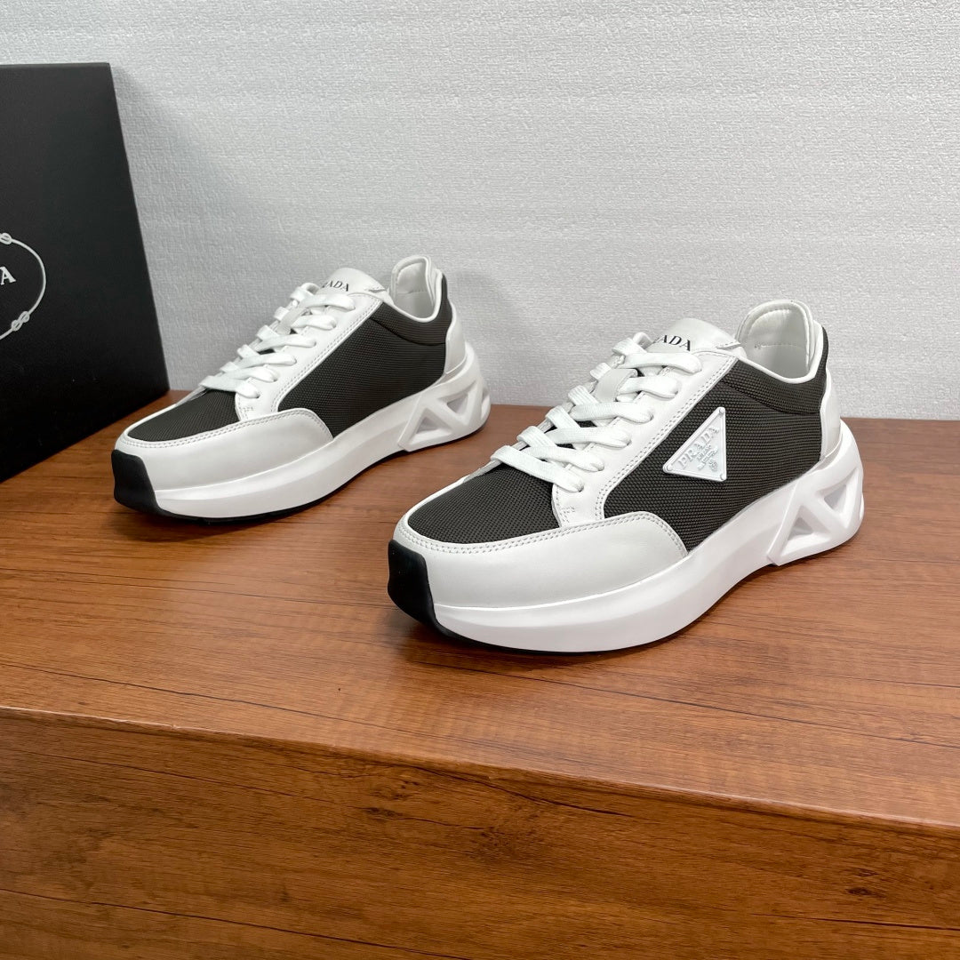 Prada unisex sneakers, black and white lace-up with chunky sole, shown pair view.