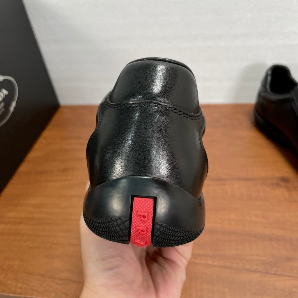 Dark leather sneaker heel with red logo label and textured rubber sole edge