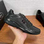 Dark leather sneaker with lace-up closure and triangular logo patch on side