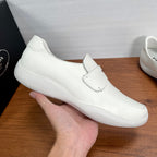 White Prada unisex slip-on loafer with strap, held in hand