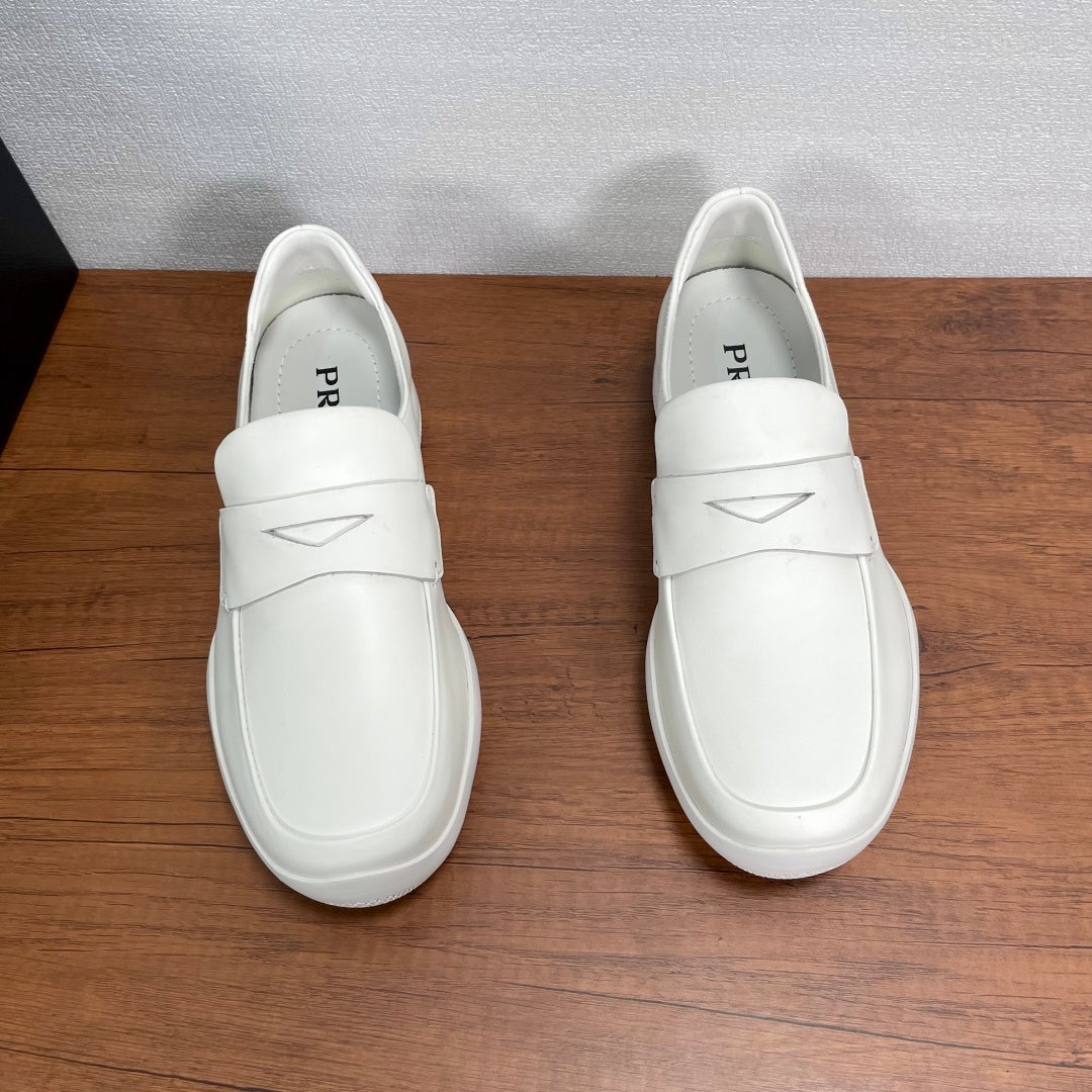 White Prada unisex slip-on loafers, front view with stitched strap detail