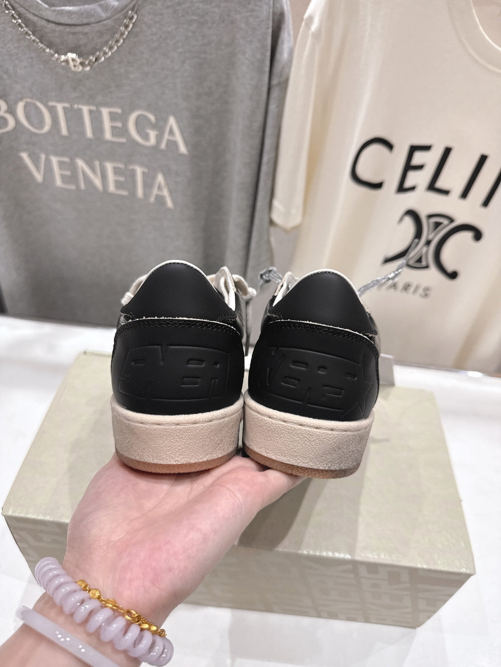 Black sneakers showing heel with tan rubber sole and lace eyelets