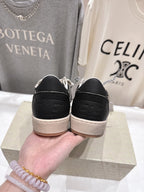 Black sneakers showing heel with tan rubber sole and lace eyelets