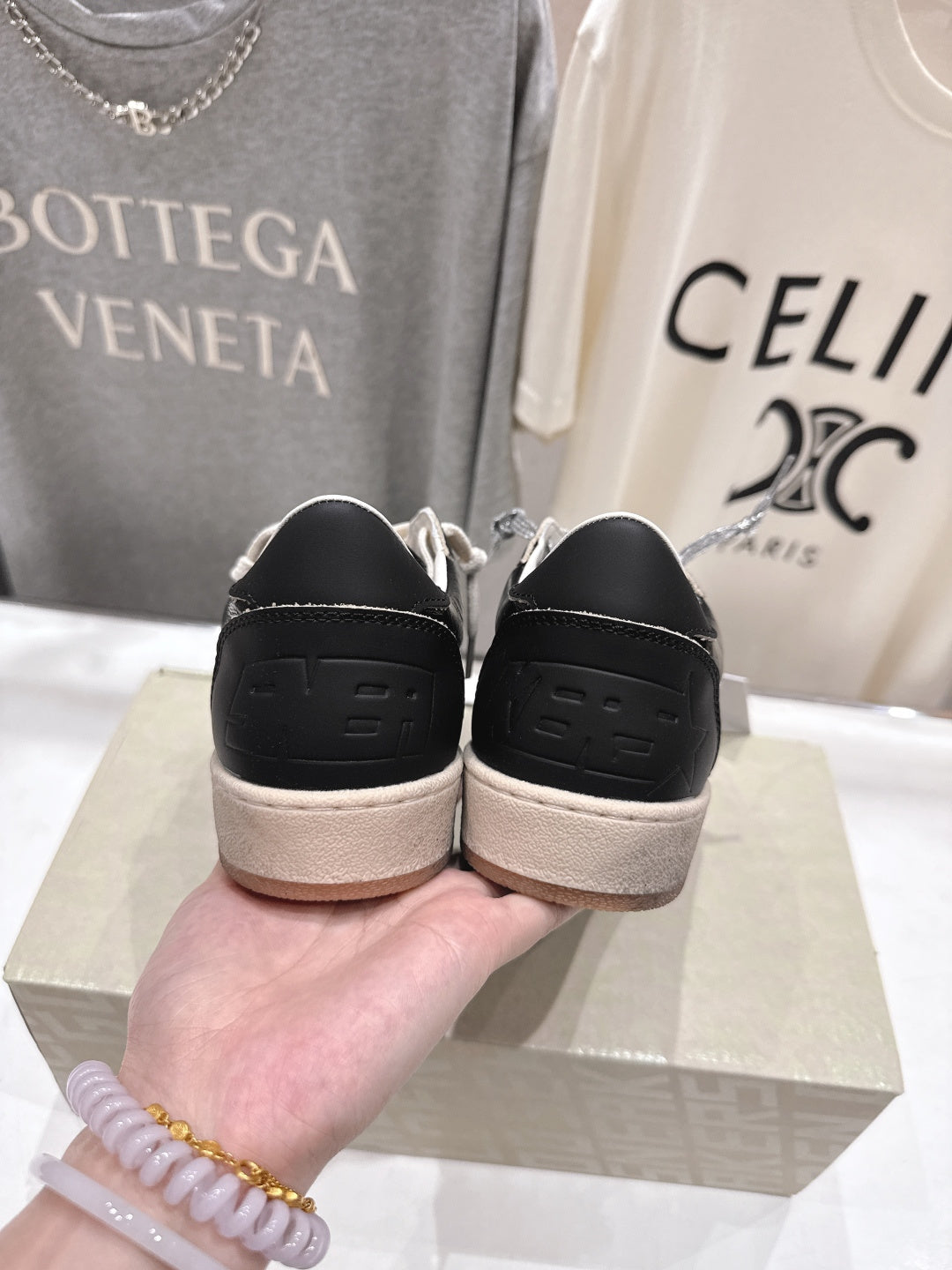 Black sneakers showing heel with tan rubber sole and lace eyelets