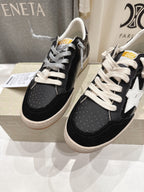 Two black low-top sneakers with white laces and white star side detail