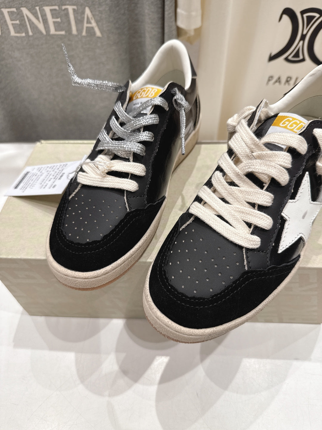 Two black low-top sneakers with white laces and white star side detail