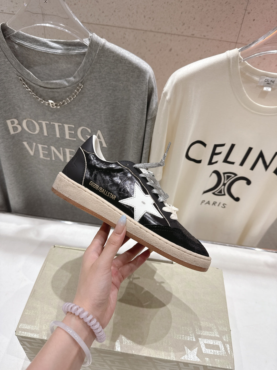 Black low-top sneaker with white star detail, white laces, tan sole
