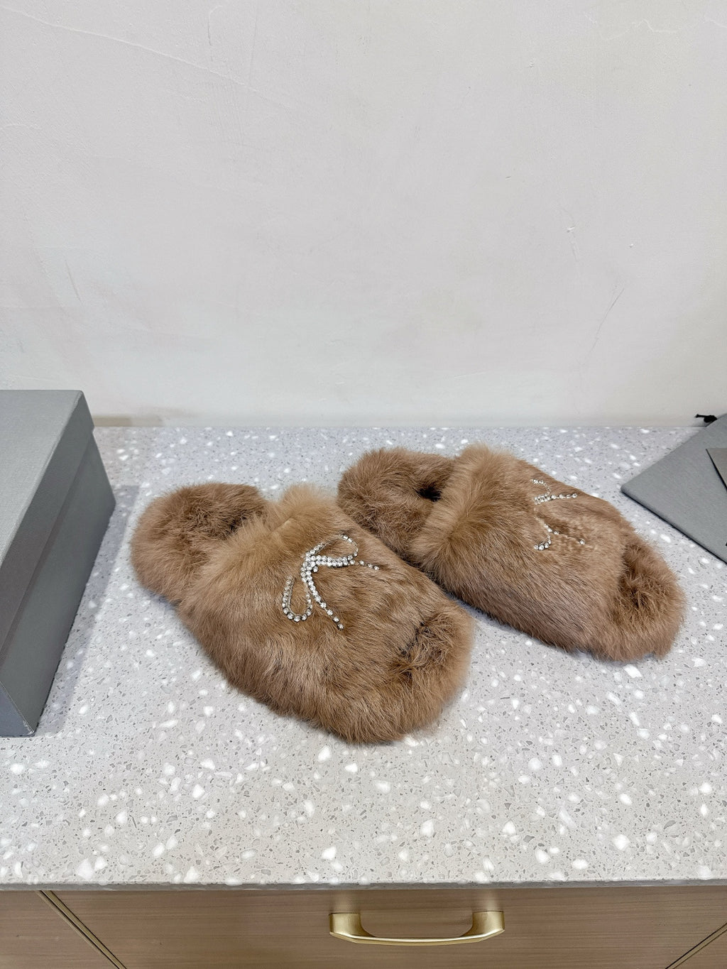 Taupe faux-fur sandals with rhinestone bow straps, angled side view