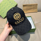 Black GG-pattern baseball cap held in hand, gold Gucci emblem on front