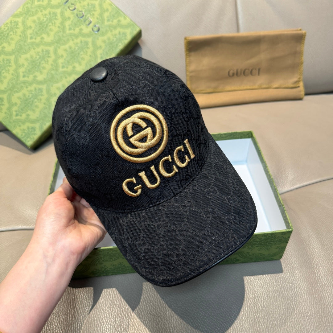 Black GG-pattern baseball cap held in hand, gold Gucci emblem on front