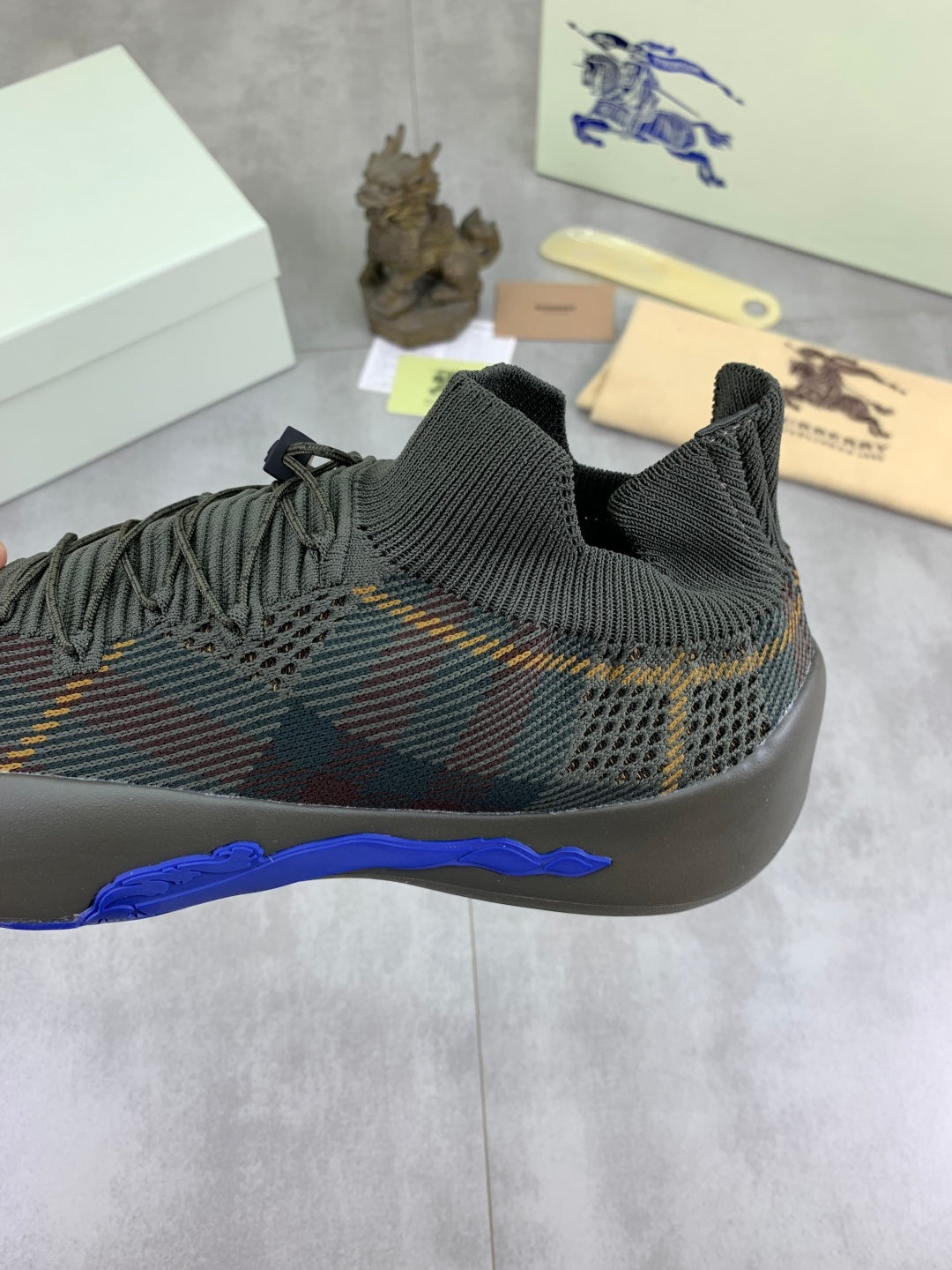 Burberry knit sneakers close-up of stretchy collar and blue sole edge on dark upper