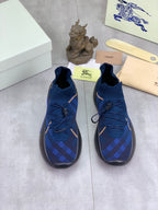 Pair of Burberry blue knit sneakers with gold trim, black soles, lace-up uppers