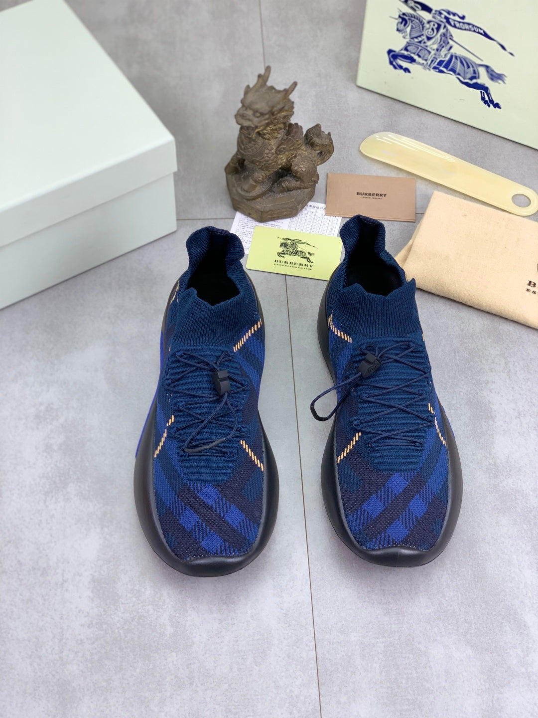 Pair of Burberry blue knit sneakers with gold trim, black soles, lace-up uppers