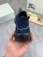 Burberry blue knit sneaker heel view with black rubber sole and gold trim detail