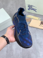Burberry blue knit sneaker with black rubber sole, gold trim and blue plaid pattern