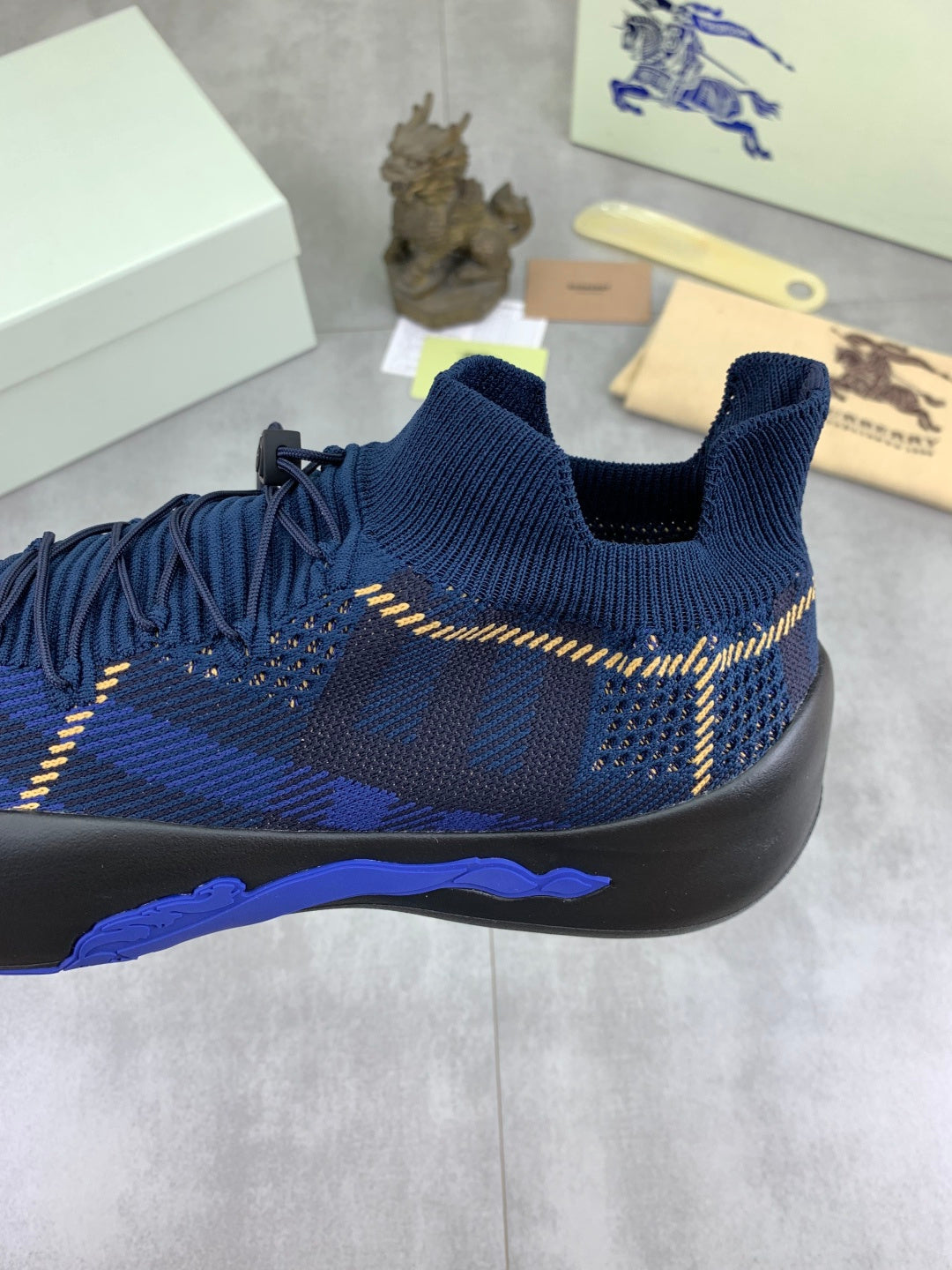 Burberry blue sock-style sneaker with gold trim, black sole and blue plaid knit