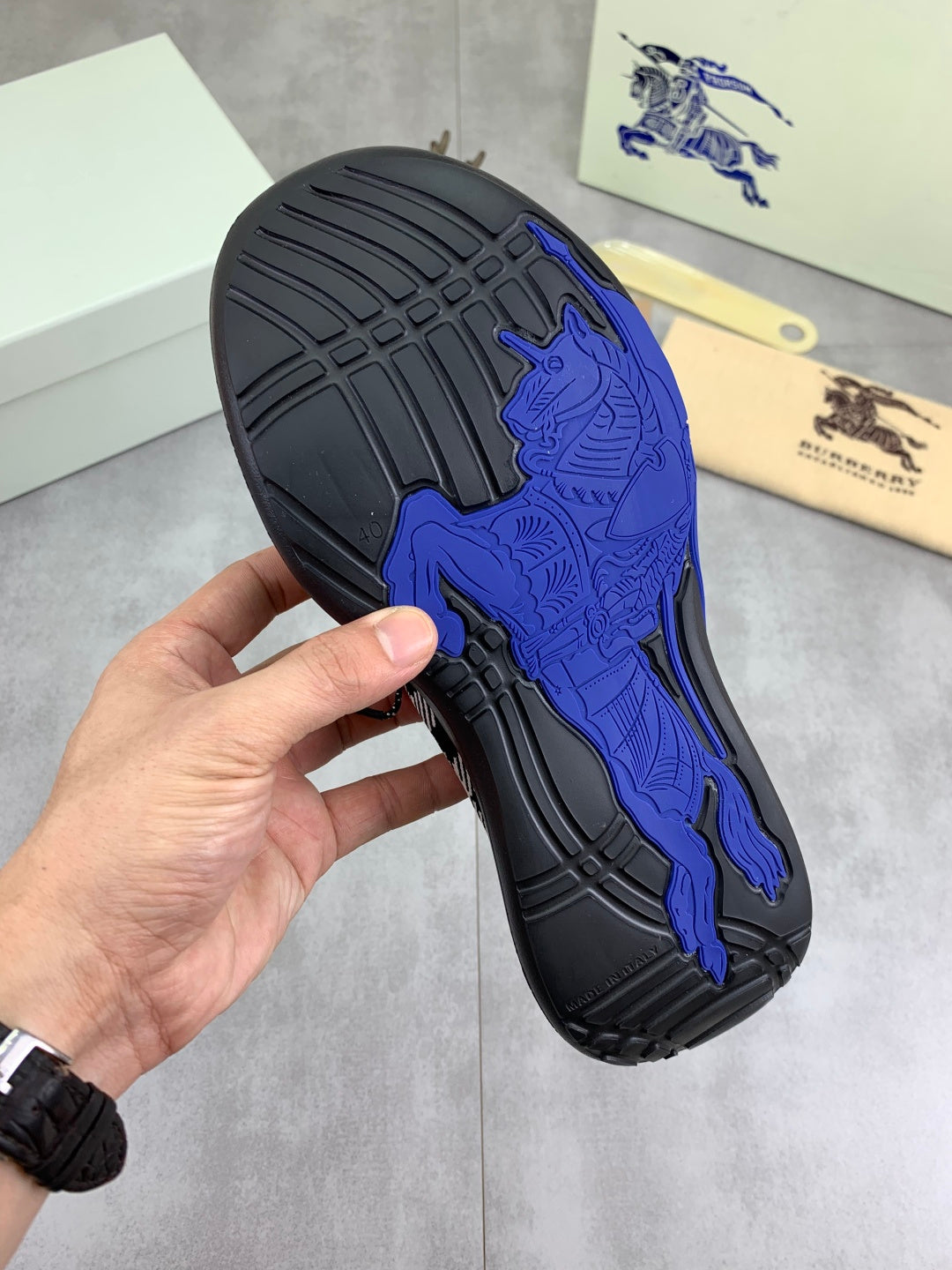 Black outsole of sneaker with raised blue bull logo grip texture