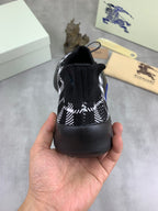 Rear view of black and white check knit sneaker with elastic heel and blue sole