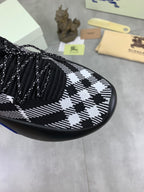 Close-up of black and white check knit upper with lace-up stitching and tassel laces