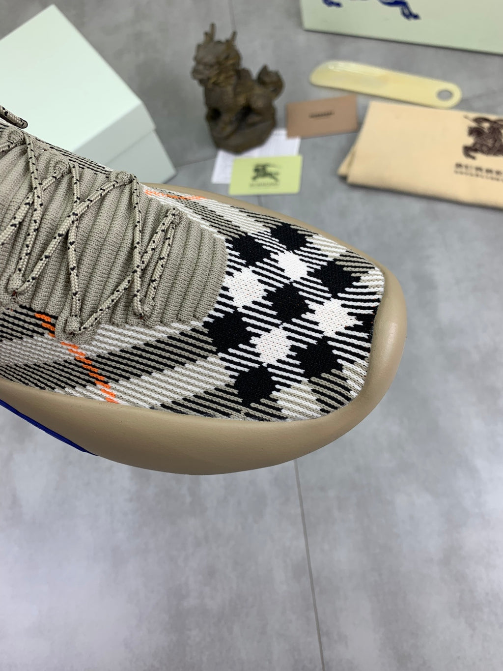 Close-up of knit upper with black-and-white checks and orange stitching details