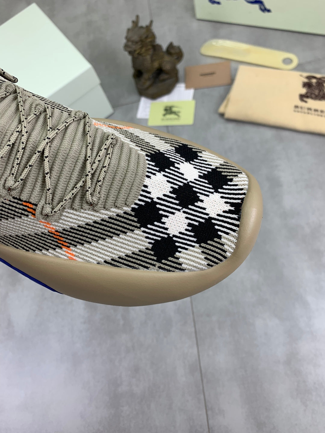 Close-up of knit upper with black-and-white checks and orange stitching details
