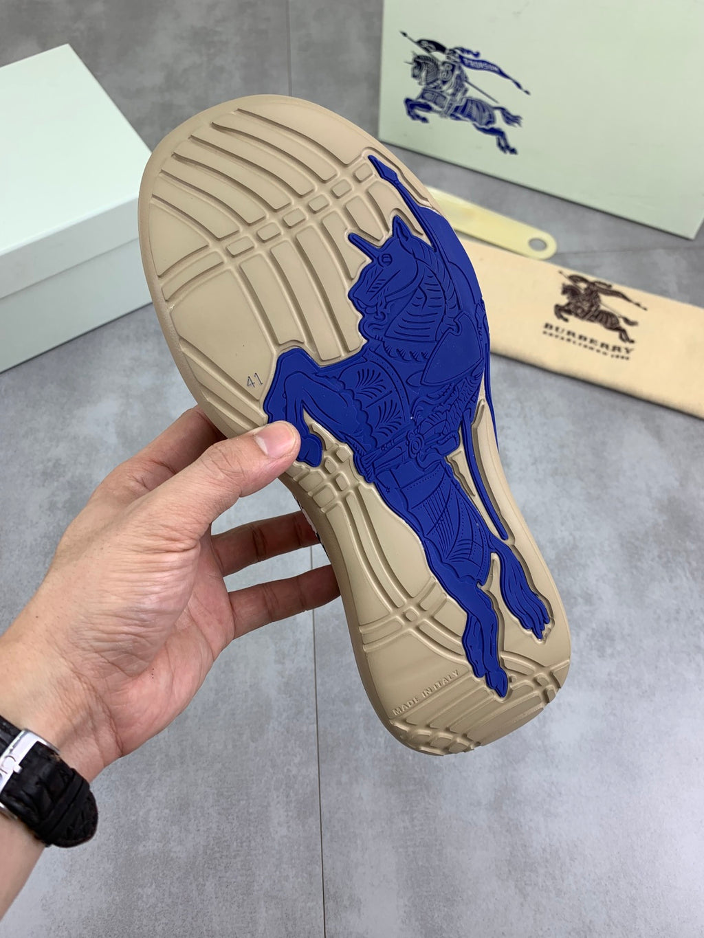 Outsole view of knit pull-on sneaker with blue rubber tread on beige base