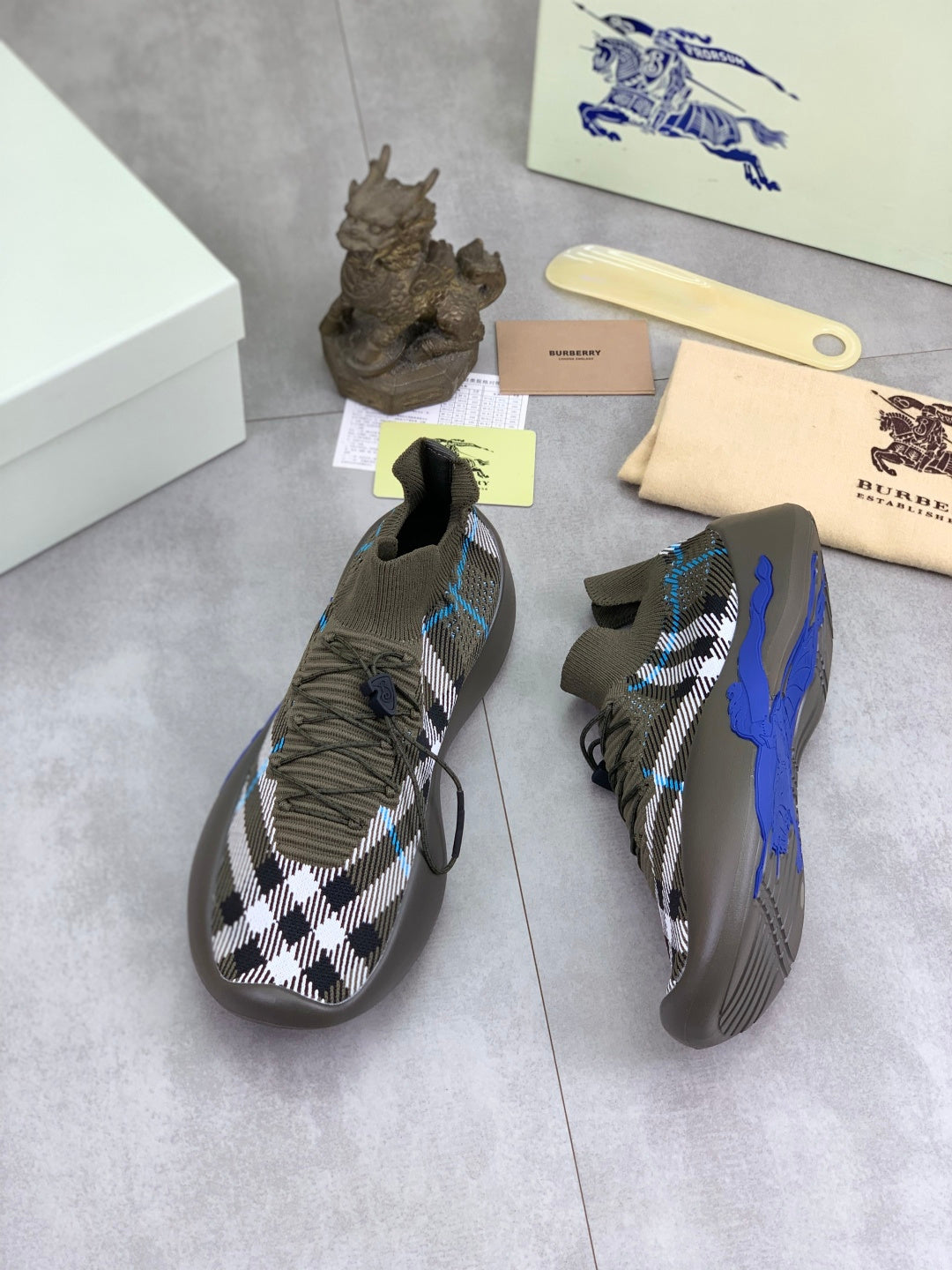 Burberry knit sneakers pair, dark olive with black-and-white check upper and blue stripe