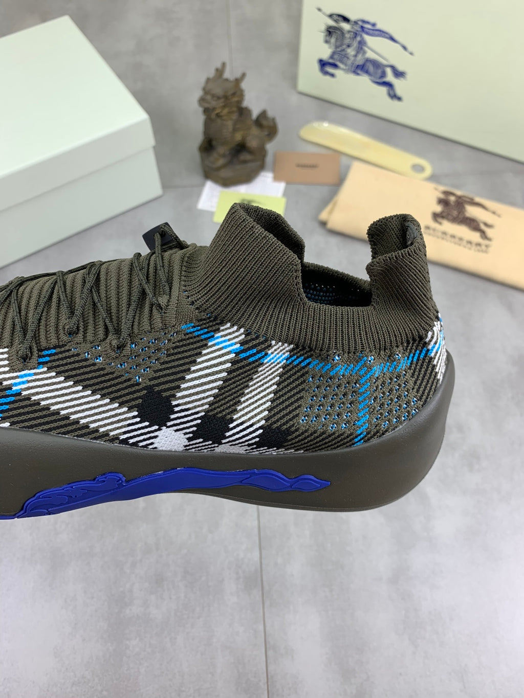 Burberry knit sneakers front view, dark olive with black-and-white check and blue trim