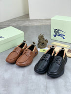 Burberry leather boat shoes in brown and black with lace eyelets, laid on boxes