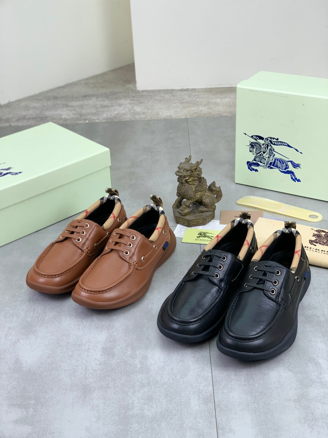 Burberry leather boat shoes in brown and black with lace eyelets, laid on boxes