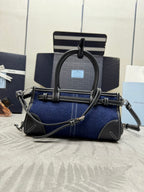 Prada navy denim handbag with black handles, logo patch, and adjustable crossbody strap