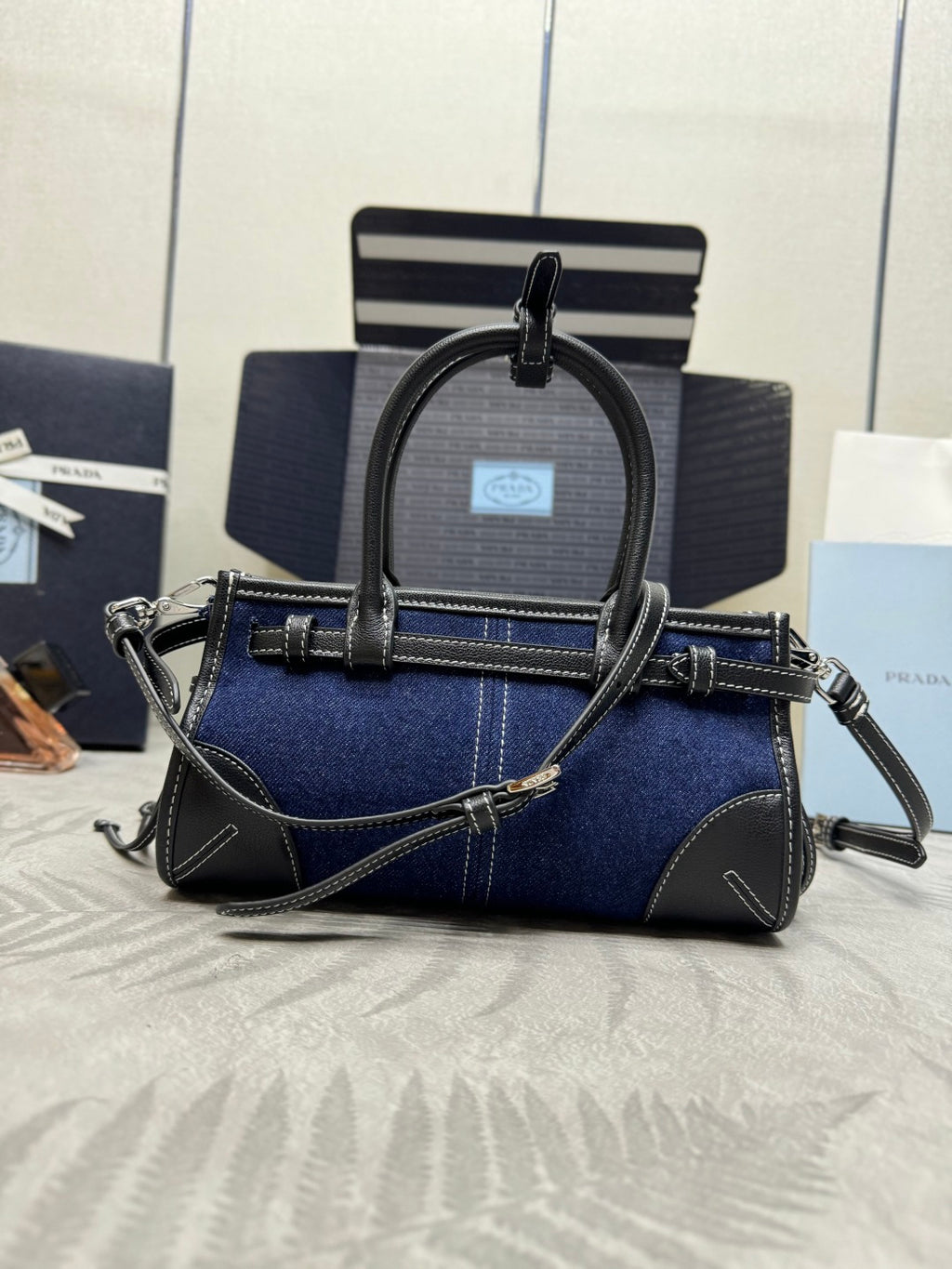 Prada mini bag in dark blue with black handles and shoulder strap, triangle logo front