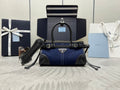Prada top-handle bag in navy denim with black trim, logo patch, and crossbody strap