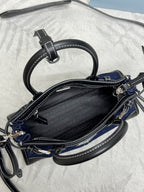 Prada mini bag open view with black zipper lining, dark blue exterior, crossbody strap