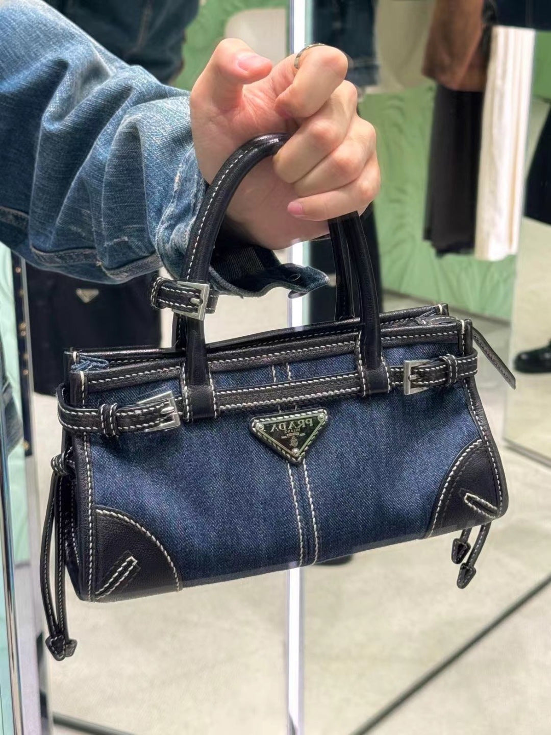 Denim handbag with top handles, front triangle logo, and side zipper pocket detailing