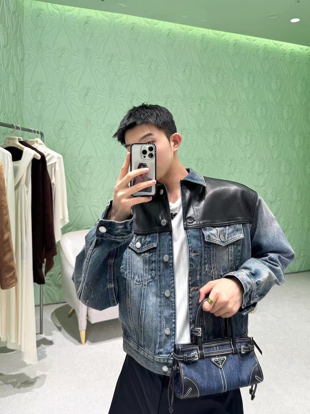 Denim Prada bag with top handles and front triangle logo, held at chest level
