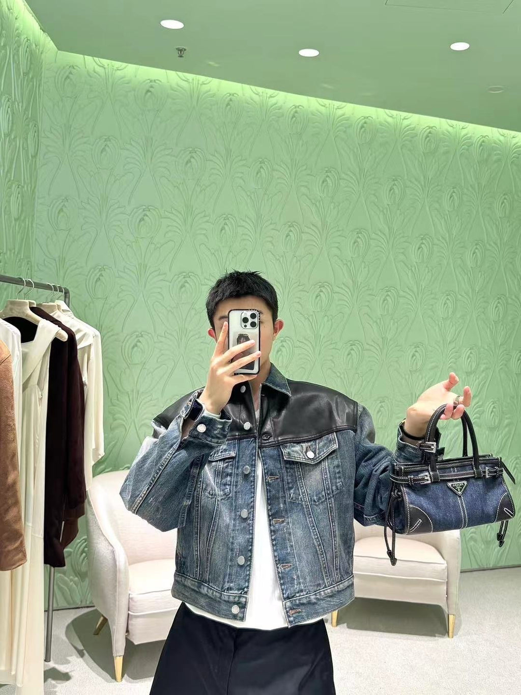 Denim Prada bag with top handles, front triangle logo, and hanging tassel straps