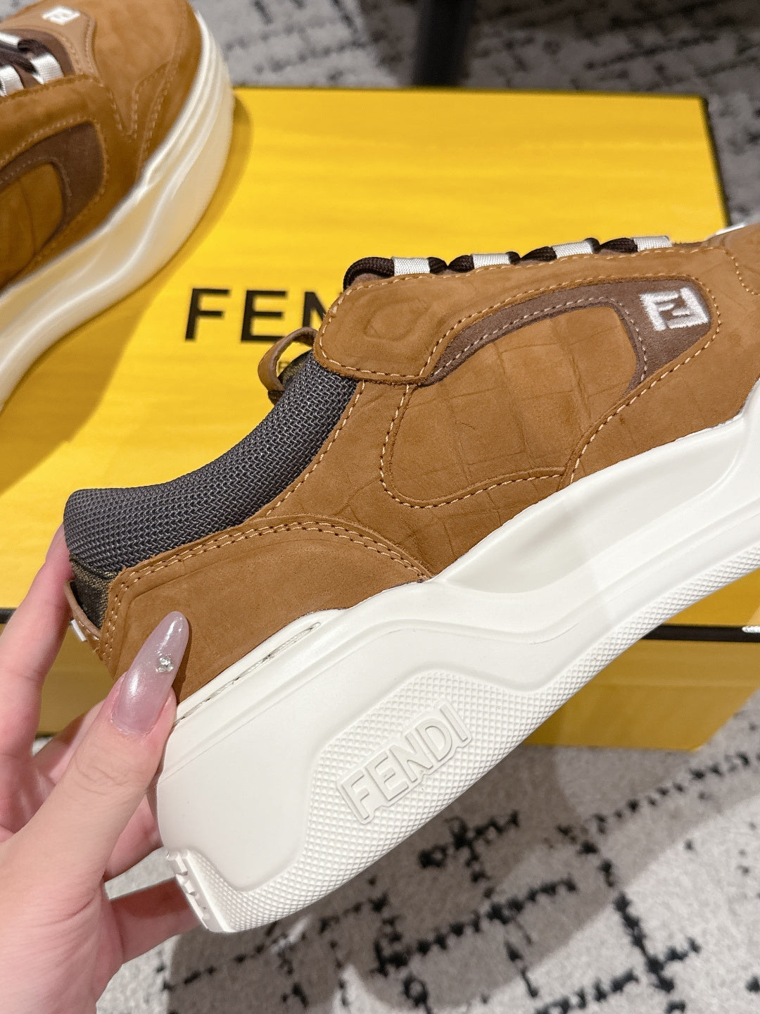 Fendi unisex sneaker side view: tan upper with gray panel, stitched sole and logo