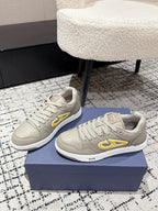 Beige Dior low-top sneakers pair, side profile with yellow logo accents